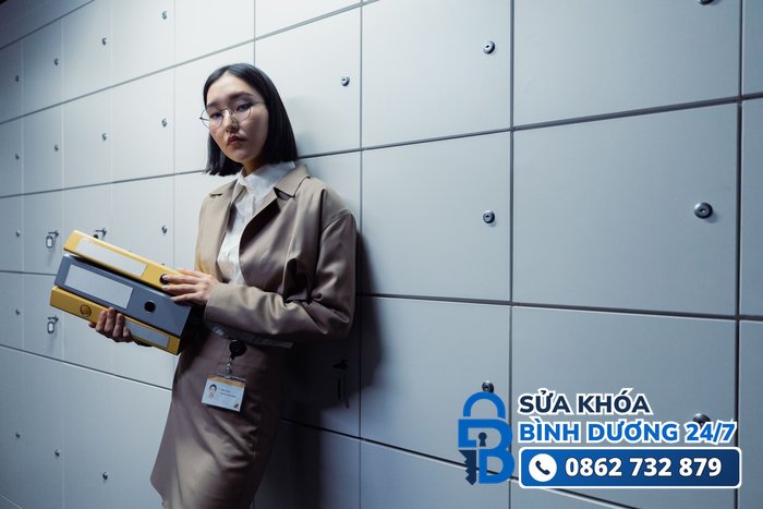 các loại khóa tủ văn phòng — nhân viên đứng cạnh dãy tủ hồ sơ có khóa